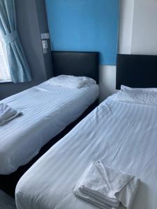 two beds in a bedroom with white sheets and towels at Abingdon Lodge Hotel in Ryde