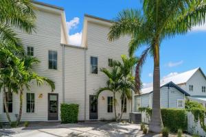 a white building with palm trees in front of it at Casa Cohiba - Ybor City Townhouse in Tampa