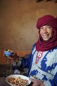 una mujer usando un hiyab sosteniendo un tazón de nueces en Green Camp Sahara, en Mhamid