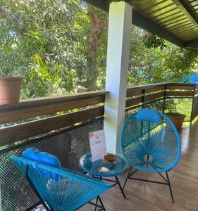 two blue chairs and a glass table on a porch at LESSENCIEL in Dzaoudzi