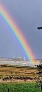 ein Regenbogen über einem Feld mit einem Boot im Wasser in der Unterkunft LE COTTAGE in Séné