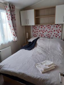 a bedroom with a bed with a red and white headboard at Cordy's Caravan in Mablethorpe