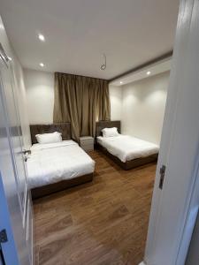 two beds in a room with wooden floors at Roma house in Al Madinah