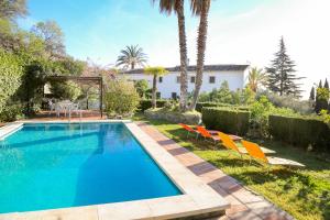 ein Swimmingpool in einem Hof mit Stühlen und einem Haus in der Unterkunft Cortijo Navas in Cómpeta