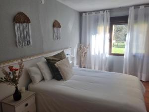 a bedroom with a white bed and a window at La Paserina in Arenas de Cabrales