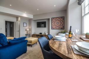 uma sala de jantar com uma mesa de madeira e cadeiras azuis em Lady Tenby - 2 Bedroom Apartment - Tenby (Windsor House) em Tenby
