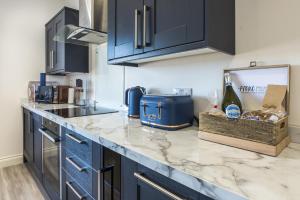 uma cozinha com armários azuis e uma bancada em Lady Tenby - 2 Bedroom Apartment - Tenby (Windsor House) em Tenby