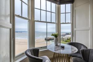 une salle à manger avec une table et des chaises et une vue sur la plage dans l'établissement Pieces of Eight - 2 Bedroom Apartment - Tenby - (Windsor House), à Tenby