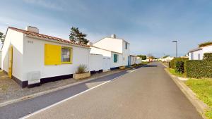 a street of white houses with yellow doors on a road at Etoile de mer avec piscine in Brétignolles-sur-Mer