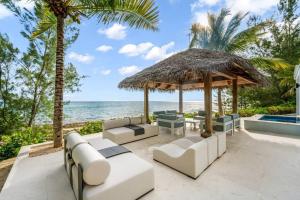 un patio con muebles blancos y vistas al océano. en Kiboko en Midland Acres