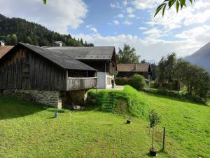an old barn on a grassy field next to a house at Chalet La Gayolle - Chalets pour 12 Personnes 96 in Saint-Gervais-les-Bains