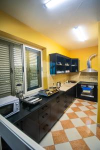a kitchen with black cabinets and a checkered floor at Shkodra Hostel in Shkodër