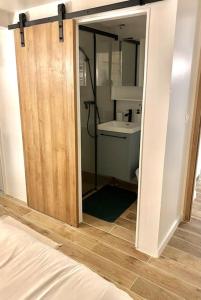 - une chambre avec une porte s'ouvrant sur une salle de bains pourvue d'un lavabo dans l'établissement Appartement charmant proche de Paris, à Villemomble
