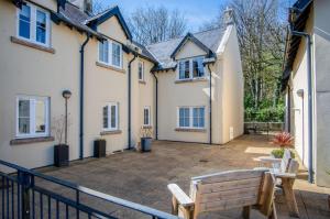a patio with two benches in front of a house at Minarvon - 2 Bedroom Apartment - Saundersfoot in Saundersfoot