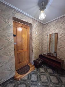 a bathroom with a wooden door and a mirror at Недорога квартира на Харківській, 32 in Sumy