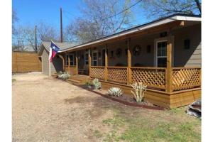 una casa con una veranda con una bandiera di Stockyards-Walk 1 Block to StockYards-Cowboy Cabin a Fort Worth