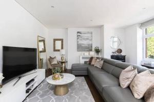 sala de estar con sofá y TV en Chic Urban Haven 3BR Flat in Clarendon Court, en Londres