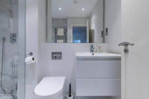 y baño con aseo, lavabo y espejo. en Chic Urban Haven 3BR Flat in Clarendon Court, en Londres