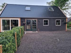 ein kleines Haus mit schwarzem Dach in der Unterkunft B&B in de Roos in Noordbergum