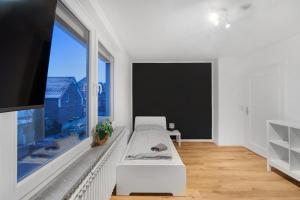 biały pokój z dużym oknem i kanapą w obiekcie Moderne Wohnung mit Garten & Küche w mieście Celle