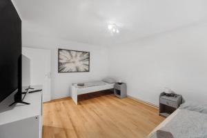 ツェレにあるModerne Wohnung mit Garten & Kücheのベッドとテレビのある白い部屋 +1枚の写真