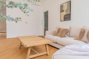 a living room with a white couch and a wooden table at Neustift Deluxe in Vienna