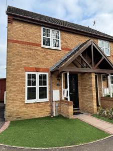 Casa de ladrillo con ventanas blancas y césped verde en Church View 2 King Bedroom Contractor Family Sky TV en Higham Ferrers