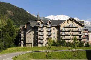 um grande edifício de apartamentos com montanhas ao fundo em Résidence Le Grand Panorama - 3 Pièces pour 6 Personnes 56 em Saint-Gervais-les-Bains