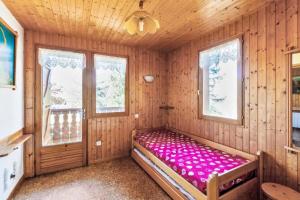 Cama en habitación de madera con 2 ventanas en Chalet le Séchet - Maeva Particuliers - 2 Pièces 4 personnes Confort 140615, en Bellentre