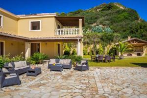 a patio with couches and chairs in front of a house at Villa Alexandros in Spartià