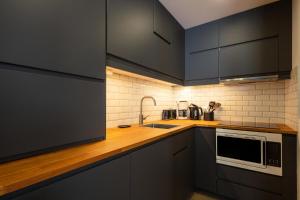 uma cozinha com armários pretos e um micro-ondas em Les Résidences de Valmorel - maeva Home - 2 Pièces 5 personnes Selection 11 em Valmorel