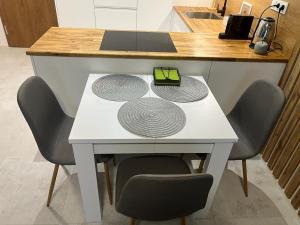 a white table with four coils on it with four chairs at Apartament Zacisze 14 in Piaseczno