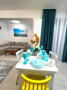 - une table blanche avec des chaises jaunes dans le salon dans l'établissement Residence 3, à Ploieşti