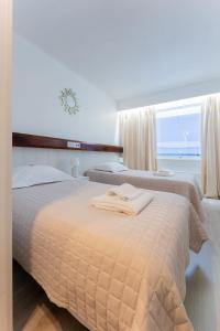 two beds in a hotel room with a window at Hotel Kemijärvi in Kemijärvi