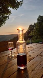 una botella de vino y una copa sobre una mesa de madera en La Table d'Elodie, en Le Béage