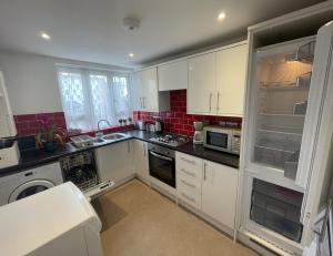 ロンドンにあるStunning Flat Close to Regents Park and Euston Station!のキッチン(白いキャビネット、オープン冷蔵庫付)