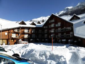 um edifício coberto de neve com um carro estacionado na frente em Résidence Combettes - 2 Pièces pour 5 Personnes 52 em Les Contamines-Montjoie