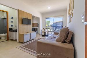 a living room with a couch and a tv and a kitchen at Aconchegante apartamento bem mobiliado PDM005 in Porto Seguro