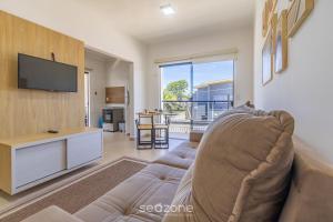 a living room with a couch and a flat screen tv at Aconchegante apartamento bem mobiliado PDM005 in Porto Seguro