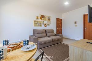 a living room with a couch and a table at Aconchegante apartamento bem mobiliado PDM005 in Porto Seguro