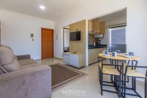 a living room with a couch and a table and a kitchen at Aconchegante apartamento bem mobiliado PDM005 in Porto Seguro