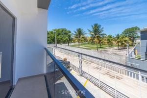 a balcony with a view of the beach and palm trees at Aconchegante apartamento bem mobiliado PDM005 in Porto Seguro