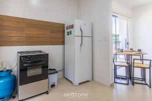 a kitchen with a refrigerator and a stove and a table at Aconchegante apartamento bem mobiliado PDM005 in Porto Seguro