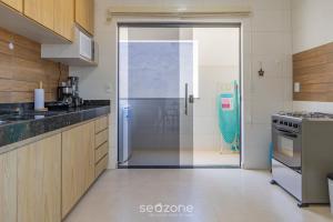 a kitchen with a sliding glass door leading to a refrigerator at Aconchegante apartamento bem mobiliado PDM005 in Porto Seguro