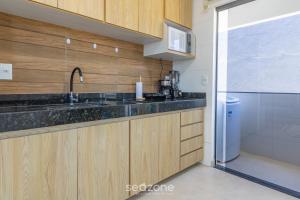 a kitchen with wooden cabinets and a sink and a shower at Aconchegante apartamento bem mobiliado PDM005 in Porto Seguro