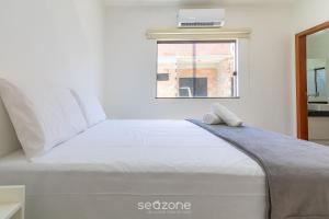 a white bed in a room with a window at Aconchegante apartamento bem mobiliado PDM005 in Porto Seguro