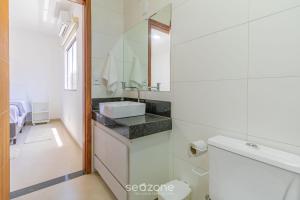 a white bathroom with a sink and a mirror at Aconchegante apartamento bem mobiliado PDM005 in Porto Seguro