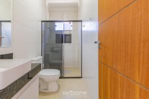 a bathroom with a toilet and a glass shower door at Aconchegante apartamento bem mobiliado PDM005 in Porto Seguro