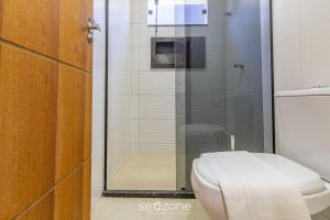 a bathroom with a toilet and a glass shower at Aconchegante apartamento bem mobiliado PDM005 in Porto Seguro