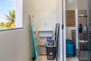 a bathroom with a sink and a trash can at Aconchegante apartamento bem mobiliado PDM005 in Porto Seguro